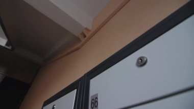 Kapalı metal posta kutuları bej duvarda, apartmanın koridorunda, son derece yakın görüşte. Mektuplar ve yazışmalar alınıyor