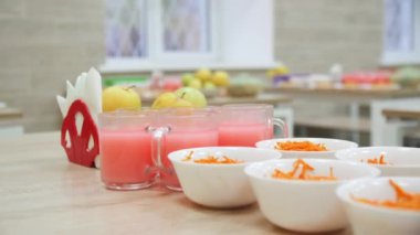 Okul kantininde havuç salatası ve meyve suyu dolu cam bardaklar. Çocuklar için sağlıklı yiyecekler