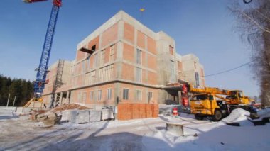 KAZAN, TATARSTAN RUSSİA - 09 Ekim 2022: Güneşli kış gününde Kazan 'da karlı inşaat sahasında tamamlanmamış modern vinç ve malzemeler