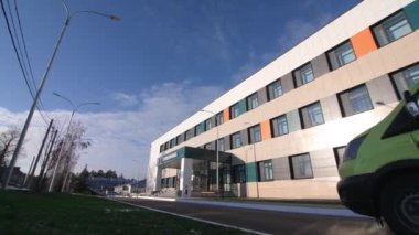 KAZAN, TATARSTAN RUSSIA - 09 Ekim 2022: Ambulans arabası açık bulutlu mavi gökyüzü altındaki hastane binasının girişine gidiyor. 9 Ekim 'de Kazan' da sağlık hizmeti