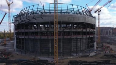 Metal çerçeveli beton bina ve inşaat alanındaki kuş bakışı vinçler. Atletik merkez