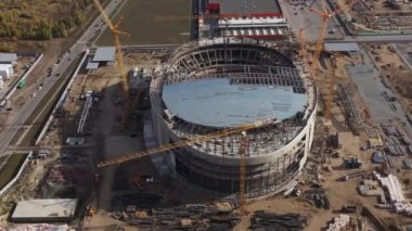 Şehrin kuş bakışı alanındaki inşaat sahasında yarı çatı spor arenası inşaatı ve çağdaş makineler