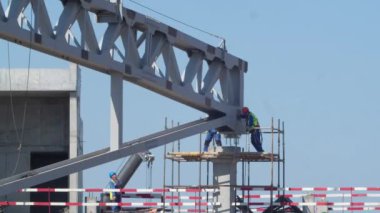 İnşaatçılar modern spor stadyumunun inşaat sahasında metal desteğe yerleştirilen devasa metal çatı iskeleti detaylarını itiyorlar