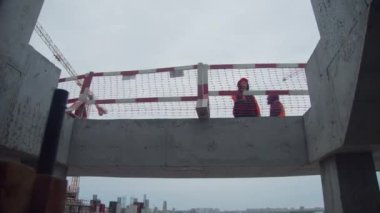 OMSK, RUSSIA - SEPTEMBER 15 2021: İnşaatçı, 15 Eylül 'de Omsk' ta, kasvetli bir günde, kentsel inşaat sahasında koruyucu çitle beton köprü üzerinde duruyor