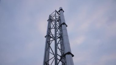 Gri bulutlu gökyüzünün altındaki güçlü gaz ve petrol rafineri tesisinde yüksek metal borular ve destek kulesi alçak açılı çekim