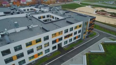 Düz çatılı büyük okul binası ve şehrin kuş bakışı manzaralı geniş pencereleri var. Çağdaş şehir mimarisi