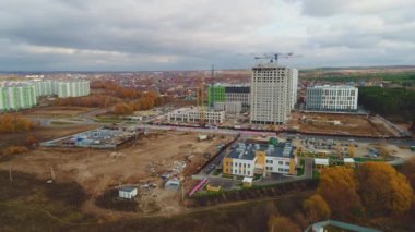 Bulutlu gökyüzü manzarası altında çağdaş şehirde yeni anaokulu ve büyük konut binaları şantiyesi