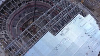 İnşaat alanında iskelet parçaları ve metal plakalarla yarı daire stadyum çatısı monte ediliyor.