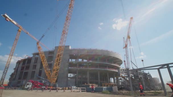 Mächtige Turmdrehkräne Und Unfertige Stadionbauten Mit Arbeitern Auf Der Großbaustelle — Stockvideo