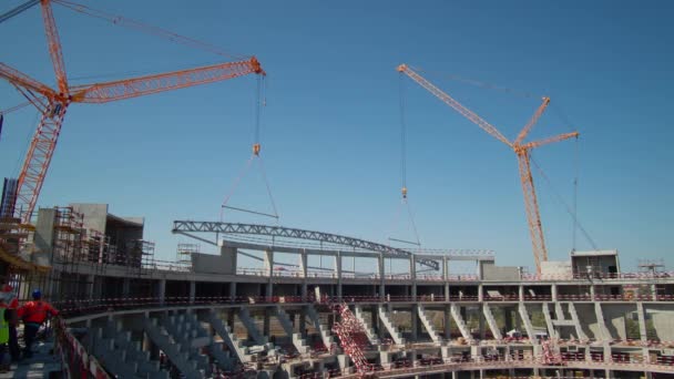 高タワークレーンは 夏の日のタイムラプスの大規模なスタジアム建設現場で金属製の屋根の詳細を持ち上げる 機械の製造 — ストック動画