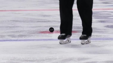 Hokey hakemi, Puck 'ı buz kontrol takımlarının maçından uzaklaştırmak için eğildi.