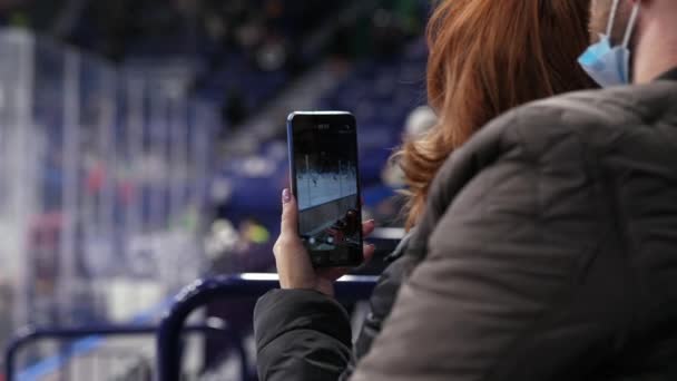 Rothaarige Frau Filmt Eishockeyspiel Mit Smartphone Und Schaut Spiel Mit — Stockvideo