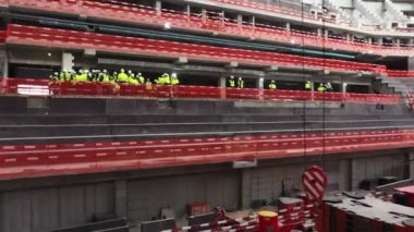 OMSK, RUSSIA - SEPTEMBER 15 2021: İnşaat alanındaki havadan görüş alanındaki spor stadyum binasının seviyesinde sarı yelek ve miğfer giyen yapıcılar
