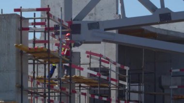 İnşaatçılar, spor arenasının inşaat sahasındaki iskelelerin üzerine büyük metal çerçeve kurulumunu kontrol ediyorlar.