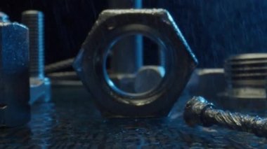 Düşen yağmur suyunun altında mavi ışıkta karanlık yüzeyde farklı bağlama araçları var. Onarım ve inşaat için donanım