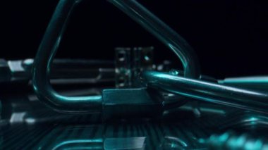 Bir grup farklı endüstriyel metal karabina karanlık stüdyo görüntüsünde masanın üzerinde. Çelik bağlanma malzemeleri yeşil ışıkta