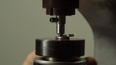 İşçi, atölyeye yakın görüş alanında değirmen makinesiyle birlikte küçük metal bir halka kuruyor. Çelik detayları oluşturma