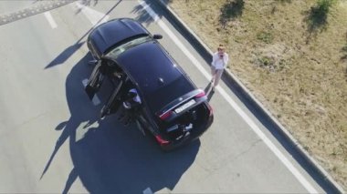 KAZAN, TATARSTAN RUSSIA - 06 Temmuz 2021: Genç kadın güneşli bir günde yol kenarında açık bagajı olan çağdaş bir arabanın yanında cep telefonu kullanıyor. 06 Temmuz 'da Kazan' da otomobille seyahat