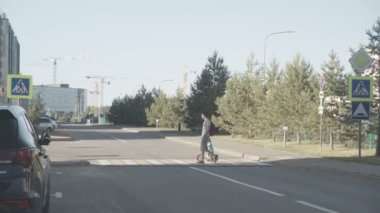 KAZAN, TATARSTAN RUSSİA - 13 Temmuz 2021: Küçük çocuklu genç bir baba yaz şehrinde boş yoldan karşıya geçiyor. Aile 13 Temmuz 'da Kazan' daki şehir parkından evine dönüyor.