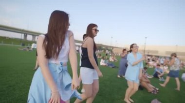 KAZAN, TATARSTAN RUSSİA - 27 Haziran 2021: Genç kadınlar yaz akşamları festivalde çimlerin üzerinde dans ederken müzik eşliğinde eğleniyorlar. 27 Haziran 'da Kazan' da insanlar dinleniyor.