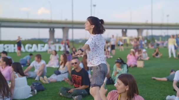 Kazan Tatarstan Russia 2021年6月27日 陽気な女の子は笑顔の段階から音楽に踊ります 若い男女は6月27日の夏の夜 花山で行われる祭りで芝生の上で休んでいる — ストック動画