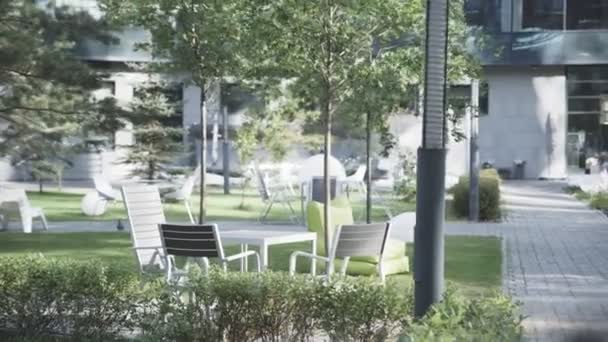 夏の日にダウンタウンの公園カフェでテーブルと椅子 緑の都市のサイトで屋外レストランの家具 — ストック動画