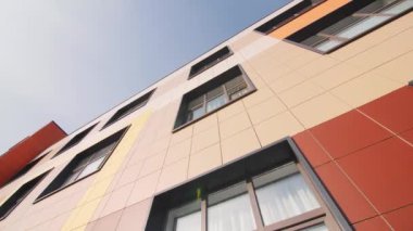 Mavi gökyüzünün altında çağdaş okul binasının camları olan renkli bir cephe. Şehir mimarisi