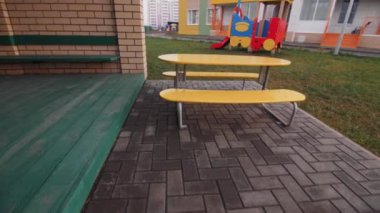 Modern anaokulunun oyun parkına yakın tuğla korkulukların olduğu boş sarı masa. Çocuk bahçesinde oynamak için ekipman