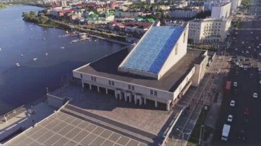 Gün batımı kuşbakışı manzaralı büyük sakin nehir kıyısındaki nehir limanı. Modern mimarisi olan harika bir şehir manzarası