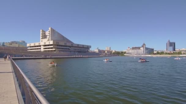 人们驾驶船只沿着城市滨水区和江港站附近平静的湖面航行 现代城镇的水上艇租赁服务 — 图库视频影像