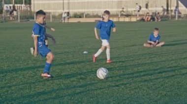 KAZAN, TATARSTAN RUSSIA - 06 Temmuz 2021: Küçük çocuk antrenman sırasında yeşil sahada takım arkadaşlarıyla futbol oynuyor. 6 Temmuz 'da Kazan' da çocuklar için spor kulübü