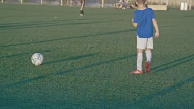 KAZAN, TATARSTAN RUSSIA - Temmuz 06 2021: Küçük sporcu yeşil sahada takım arkadaşıyla ağır çekimde futbol oynuyor. Kazan 'da 6 Temmuz' da çocuklar için spor etkinliği