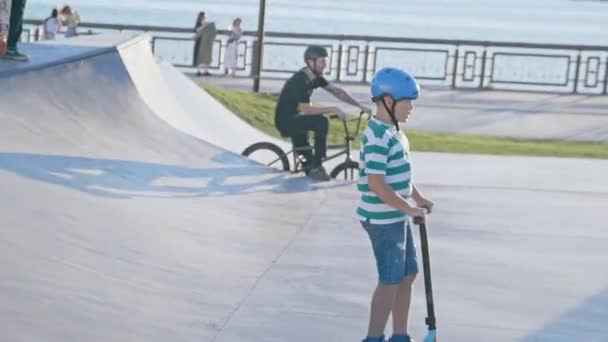 Kazan Tatarstan Russia 2021年7月6日 日落时分 带着头盔的孩子骑着脚踢滑板车沿着球场行驶 2006年7月6日 男孩在喀山的现代运动场上玩得很开心 — 图库视频影像