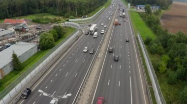 Ormanın karşısındaki geniş kırsal otoyolda trafik var. İnşaat alanı ve üst geçitten yaya köprüsü manzaralı. Kırsal kesimde otoyol