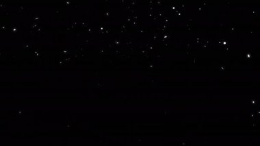  Kar yağıyor. Odaklanamayan ve maviye boyanmış kar taneleri siyah arka planda dönüp parlıyor. Siyah zemine düşen Noel Karı. 4K 'da kar örtüsü. Alfa kanalı