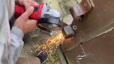 Kapıdaki kilidi öğütücüyle kesen adam. Öğütücü kıvılcımlar 