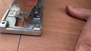 Yakın çekim. Marangoz elektrikli testereyle tahta testeresi kesiyor. Testereyle odun kesen bir adama yaklaş.