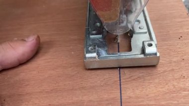 Yakın çekim. Marangoz elektrikli testereyle tahta testeresi kesiyor. Testereyle odun kesen bir adama yaklaş.