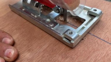 Yakın çekim. Marangoz elektrikli testereyle tahta testeresi kesiyor. Testereyle odun kesen bir adama yaklaş.