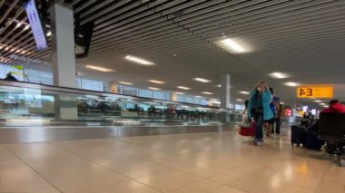 Amsterdam Hollanda 11 Kasım 2021: Schiphol Havaalanı. Koruyucu maskeli insanlar havaalanı koridorunda uçmak için yürüyorlar.