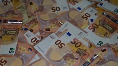 Ağır çekim. 50 Euro 'luk banknotlar yığınla paranın üstüne düşüyor.