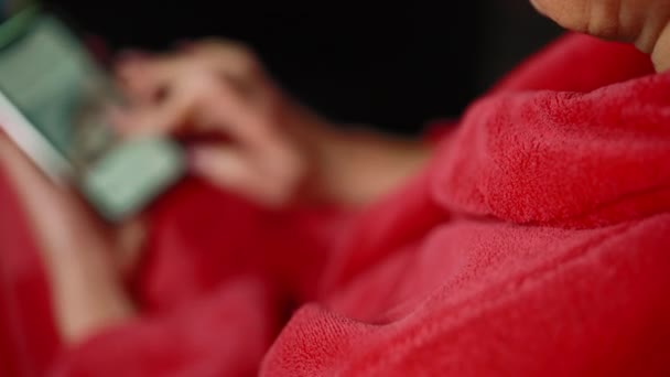 黒い背景に対して彼女の電話でインターネットを使用して赤いコートの女性のクローズアップショット 選択的フォーカス — ストック動画