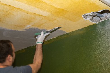 Seçici odaklanma. Sıvacı tamir ve onarım sırasında tavana alçı yapıştırır
