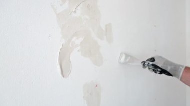 Close-up shoot. Plasterer puttying holes in the wall