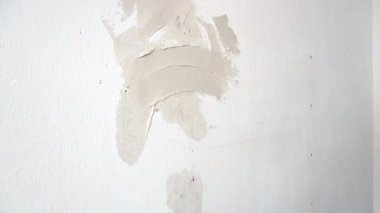 Yakın plan çekim. Sıvacı duvarda delikler açıyor.