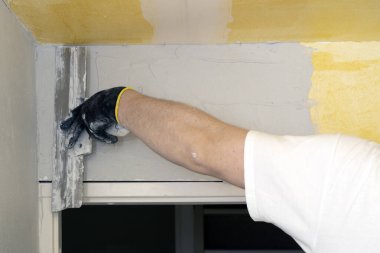 Kapatın. Sıvacı duvara macun bıçağıyla sıva yapıyor.