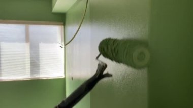 Yakın çekim. Duvar boyası. Boyacı boya silindiriyle duvar boyar.