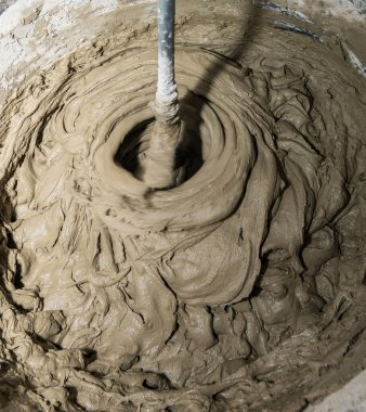 Industry background. Construction site. Mixing tile adhesive with a construction mixer