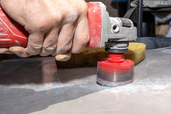 The tiler drills porcelain stoneware with a diamond crown. Close-up, selective focus.