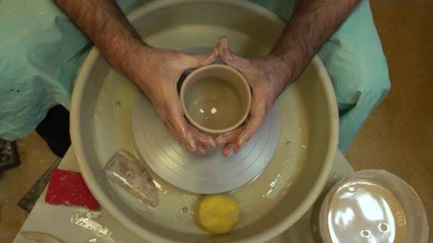 Olarul lucrează pe o roată de ceramică. Boluri de lut din argilă moale colorată — Videoclip de stoc